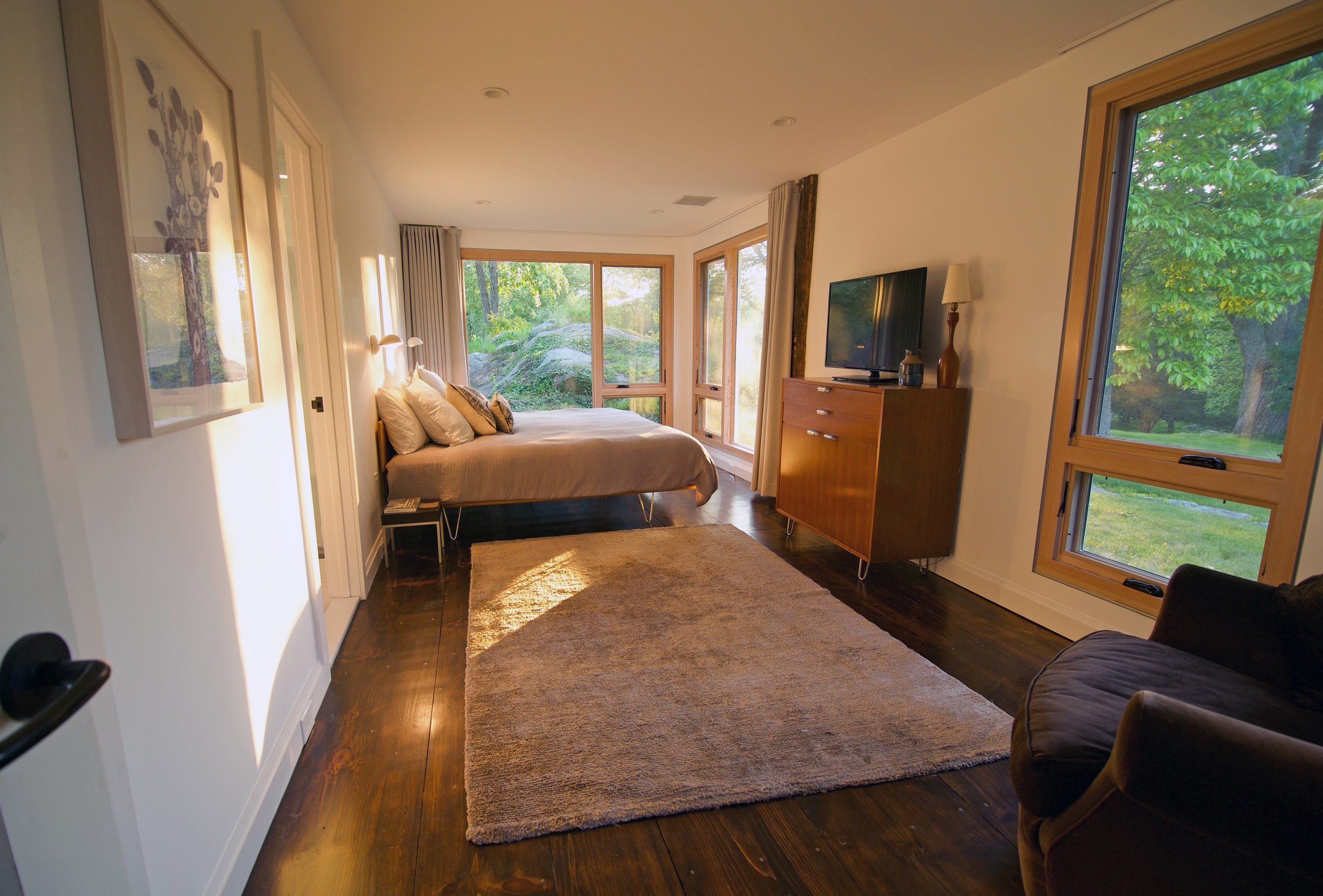 Warm residential bedroom opening to a wooded site